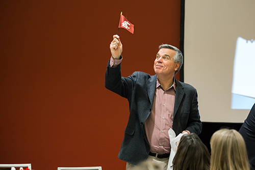 man waves a small WSU flag at the SPA annual meeting
