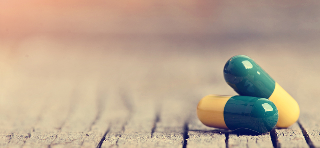 detail image of two pill capsules displayed on wood background